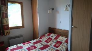 a bedroom with a bed with a red and white quilt at Edelweiss Chalets De La Vallee D'or - 2 Pièces pour 4 Personnes 34 in Valloire