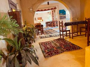 a living room with a table and chairs and a plant at Aghurmi Siwa Ecolodge & Salt Cave in Siwa