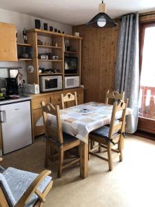 a kitchen with a table and some chairs and a table and a table at Résidence Betelgeuse - Studio pour 4 Personnes 34 in Valloire
