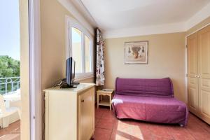 sala de estar con silla púrpura y TV en Les Issambres Lauriers - maeva Home - Studio 4 personnes Confort 77 en Les Issambres