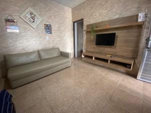 Una sala de estar con un sofá y un televisor de pantalla plana. en Casa com Piscina Privativa em Bertioga 2 Suítes e Wi-Fi Bem próxima à praia, en Bertioga