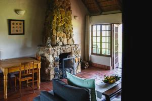 sala de estar con chimenea de piedra y mesa en Ardmore Guest Farm en Champagne Valley