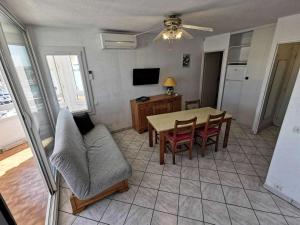 een woonkamer met een tafel en stoelen en een televisie bij Résidence TERRASSES DE LA MEDITERRANEE 1 - 2 Pièces pour 5 Personnes 54 in Port Leucate