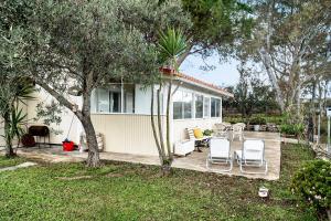 una casa con terraza, sillas y árboles en Kite beach house, en Lefkada