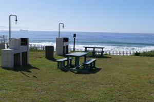 dos mesas de picnic en la playa cerca del océano en Beach Club Unit 207, en Mossel Bay