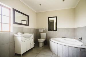 a bathroom with a tub and a toilet and a sink at Ardmore Guest Farm in Champagne Valley