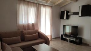 een woonkamer met een bank en een televisie bij Lion Apartment in Limenas