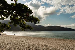 una playa con el océano y las montañas en el fondo en Aluguel Temporada praia Maresias, en São Sebastião