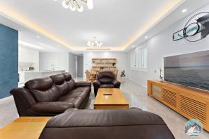 a living room with a leather couch and a large television at Aircabin - Fairfield - Modern - 6 Bedrooms House in Fairfield