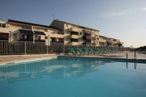 a swimming pool with chairs and a building in the background at Résidence Bleu Marine - maeva Home - Appartement 2 pièces 4 personnes Confort MAE-2510 in Lacanau