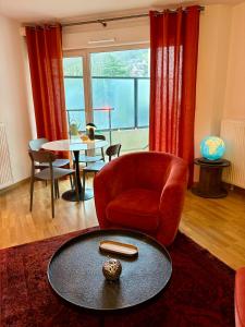 - un salon avec une chaise rouge et une table dans l'établissement Appartement proche centre parking & terrasse, à Besançon