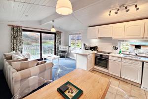 a kitchen and living room with a couch and a table at Lapwing chalet in Crianlarich