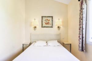 ein Schlafzimmer mit einem weißen Bett und zwei Lampen in der Unterkunft Les maisons Le Rouret - maeva Home - Maison 3 pièces 6 personnes Sélection MAE-3026 in Grospierres