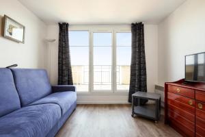 Una sala de estar con un sofá azul y una ventana. en Résidence Port Guillaume - maeva Home - Studio 2 personnes Sélection MAE-3802, en Dives-sur-Mer