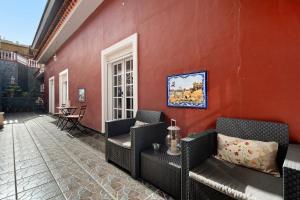 una pared roja con sillas de mimbre en un patio en La Planta Vieja, en La Orotava