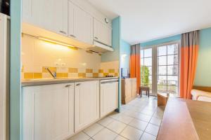 eine Küche mit weißen Schränken und ein Esszimmer in der Unterkunft Les Maisons de Belle Dune - maeva Home - Maison 2 pièces 5 personnes Sélection MAE-4185 in Fort-Mahon-Plage