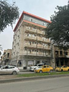 a large building with cars parked in front of it at Malik Dijlah Hotel in Baghdād