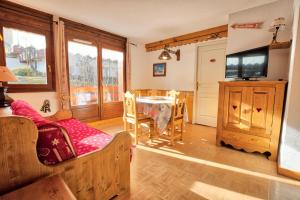 a living room with a table and a tv at Les Chalets Des Evettes - 3 Pièces pour 6 Personnes 64 in Notre-Dame-de-Bellecombe