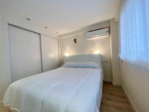 a white bed in a room with a window at White House Nervion in Benidorm