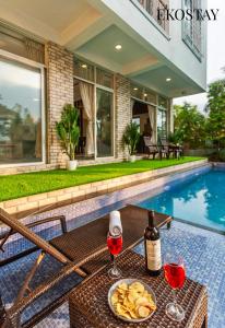 a table with two glasses of wine next to a swimming pool at EKOSTAY - Casa De Reva in Lonavala