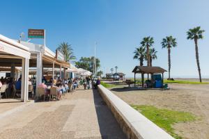 a group of people sitting at tables on a sidewalk near the beach at OceanVibe Loft MalagaFlat in Málaga