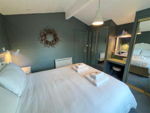 a bedroom with a white bed with two towels on it at Lapwing chalet in Crianlarich