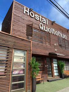 un edificio de avanzada del albergue con un banco frente a él en Hostal Queltehue en Ancud