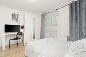 una camera bianca con un letto, una sedia e una TV di Cozy Studio Batorego by Rent like home a Varsavia