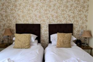 two beds in a bedroom with two lamps on tables at The View Guest House (Adults Only) in Llandudno