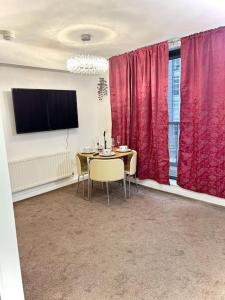 comedor con mesa y cortinas rojas en Beautiful One Bedroom Flat In Central London, en Londres