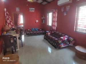 a living room with two couches in a red room at Om Gajanan Farms in Nerur