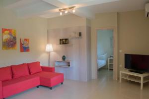 a living room with a red couch and a television at Villa Orama in Nea Potidaea