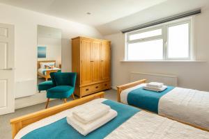 1 Schlafzimmer mit 2 Betten, einem Stuhl und einem Schreibtisch in der Unterkunft Brighton & Hove Beach - group or family fun in Brighton & Hove