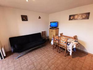 uma sala de estar com um sofá preto e uma mesa em Résidence MAISONS DE LA PLAGE - Maisons & Villas pour 6 Personnes 074 em Port Leucate