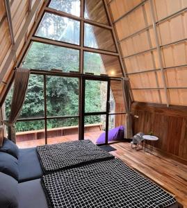 Habitación con sofá y ventana grande. en Luxury cabin and cafe hutan pinus rahong en Palayangan