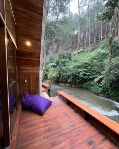 una terraza de madera con vistas al río en Luxury cabin and cafe hutan pinus rahong en Palayangan