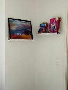 three books are on top of a white wall at Duplex luxury à 15’ JOP stade de France in Saint-Ouen