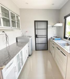  La cuisine est équipée de placards blancs et d'un réfrigérateur. dans l'établissement issara2, à Udon Thani