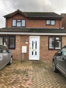 a brick house with a white door and two cars parked at House on the corner in Thame