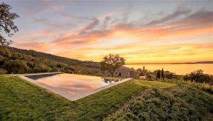 a swimming pool on a lawn with a sunset at Villa Polvese Luxury Estate in Magione