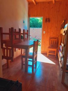 comedor con mesa de madera y sillas en Cabañas Ema Luz & La Soñada en Gobernador Roca