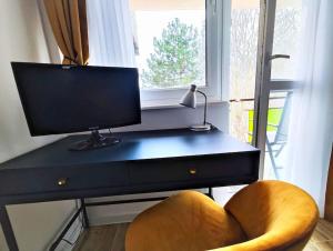 a desk with a monitor and a chair next to a window at Komfortowy Apartament Narie in Kretowiny