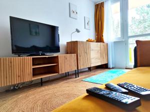 a living room with a tv and two remote controls at Komfortowy Apartament Narie in Kretowiny