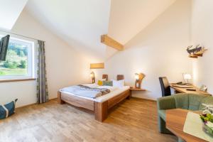 a bedroom with a bed and a desk in a room at Sontheims Naturhotel & Spa in Maierhöfen