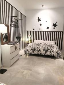 ein Schlafzimmer mit einem Bett und einer schwarz-weiß gestreiften Wand in der Unterkunft Suite Parking según disponibilidad in Sevilla
