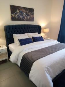 Apartment F14 - Samarah Resort في السويمة: غرفة نوم بسرير كبير مع وسائد زرقاء