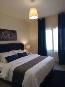 Apartment F14 - Samarah Resort في السويمة: غرفة نوم بسرير كبير مع ستائر زرقاء