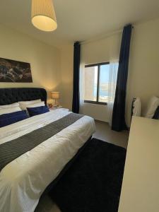 Apartment F14 - Samarah Resort في السويمة: غرفة نوم بسرير كبير ونافذة