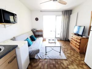 sala de estar con sofá y TV en Résidence LES NEFS DES SABLES - Studio pour 5 Personnes 924, en Port Leucate