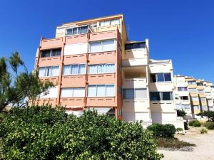 un edificio de apartamentos alto con árboles delante de él en Résidence LES NEFS DES SABLES - Studio pour 5 Personnes 924, en Port Leucate